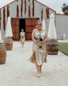 bridesmaid walking down the aisle with a rustic barn in the background